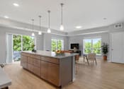 Thumbnail 9 of 61 - A modern kitchen with a wooden island and pendant lights.