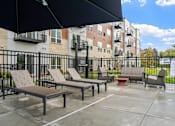 Thumbnail 25 of 61 - A patio with a black umbrella and a bench.
