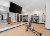 Thumbnail 61 of 61 - A gym with a variety of equipment including a bench, weights, and a television.