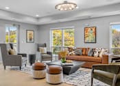 Thumbnail 57 of 61 - A living room with a brown couch, grey armchairs, and a coffee table.