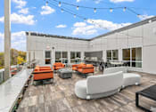 Thumbnail 56 of 61 - A patio with orange and white furniture and a black table.