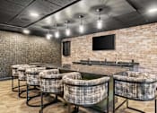 Thumbnail 47 of 61 - A room with a brick wall and a bar with stools.