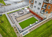 Thumbnail 46 of 61 - A small grassy area surrounded by a fence and a building.