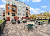 Thumbnail 48 of 61 - A patio with chairs and a table is in front of a building.