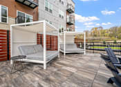 Thumbnail 49 of 61 - A patio with a white couch and a black table.