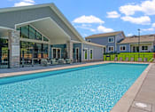 Thumbnail 14 of 76 - A swimming pool in front of a building with a white roof.