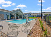 Thumbnail 18 of 76 - A pool area with chairs and a building in the background.