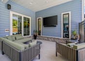 Thumbnail 19 of 76 - A patio with a couch, a table, and a television.