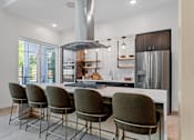 Thumbnail 30 of 76 - A modern kitchen with a large island and chairs.