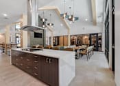 Thumbnail 36 of 76 - A modern kitchen with a large island and a range hood.