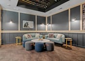 Thumbnail 45 of 76 - A modern living room with a grey sofa, a round table, and a grey ottoman.