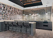 Thumbnail 47 of 76 - A bar area with a row of chairs and a television on the wall.