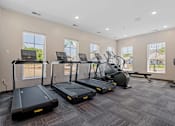 Thumbnail 50 of 76 - A spacious gym with treadmills, elliptical machines, and a stationary bike.