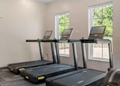 Thumbnail 54 of 76 - Three treadmills are lined up in a row in a room with windows.