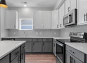 Thumbnail 57 of 76 - A kitchen with white cabinets and black appliances.