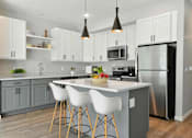 Thumbnail 67 of 76 - A modern kitchen with a large island and white chairs.