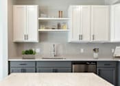 Thumbnail 68 of 76 - A kitchen with a marble countertop and grey cabinets.