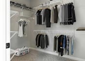 Thumbnail 74 of 76 - A white closet with clothes hanging on shelves and a Converse bag on the floor.