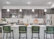 Thumbnail 13 of 32 - A kitchen with a white countertop and green barstools.