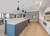 Thumbnail 18 of 30 - A kitchen with a large island and wooden floors.