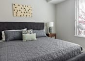 Thumbnail 8 of 30 - A bed with a black headboard and grey comforter with four pillows on it.