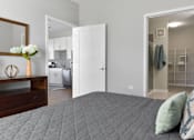 Thumbnail 9 of 30 - A bedroom with a bed, a dresser, and a mirror.