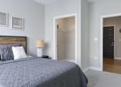 Thumbnail 7 of 30 - A bedroom with a bed, lamp, and two doors.
