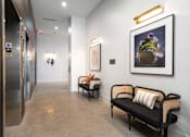 Thumbnail 42 of 43 - A hallway with a bench, a painting, and a framed picture on the wall.