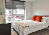 Thumbnail 9 of 43 - A bedroom with a large bed and a window overlooking a construction site.