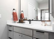 Thumbnail 36 of 43 - A bathroom with a white counter top and a large mirror.