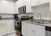 Thumbnail 3 of 42 - A kitchen with white cabinets and a granite countertop.