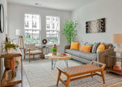 Thumbnail 8 of 42 - A living room with a grey couch, a wooden coffee table, and a large window.