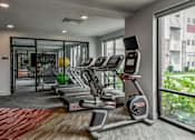 Thumbnail 32 of 42 - A gym with treadmills and a view of a building outside.