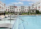 Thumbnail 37 of 42 - Resort-style swimming pool with lounge chairs at The View on Collins apartments for rent in Lansing, MI