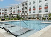 Thumbnail 1 of 42 - Pool with lounge chairs and safety rails at The View on Collins luxury apartments in Lansing, MI