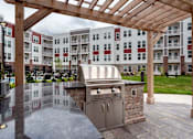 Thumbnail 39 of 42 - A BBQ grill is situated under a wooden pergola in a courtyard.