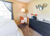 Thumbnail 8 of 43 - A bedroom with a bed, chair, and dresser.