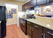 Thumbnail 4 of 43 - A kitchen with a black refrigerator and brown cabinets.