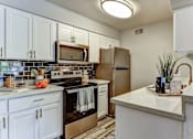 Thumbnail 7 of 27 - A kitchen with white cabinets and a stainless steel refrigerator.