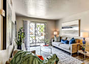 Thumbnail 9 of 27 - A living room with a couch, a coffee table, and a painting on the wall.