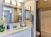 Thumbnail 13 of 27 - A bathroom with a sink, mirror, and shower.