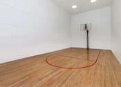 Thumbnail 16 of 27 - A basketball hoop is mounted on a pole in a room with a wooden floor.