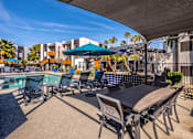 Thumbnail 20 of 27 - A poolside area with chairs and a table.