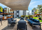 Thumbnail 22 of 27 - A patio with a black couch and chairs under a white awning.