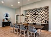 Thumbnail 12 of 36 - Community clubhouse with modern dining room with a wooden table and grey chairs