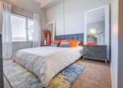 Thumbnail 3 of 24 - A bedroom with a large bed and a mirror on the wall.