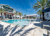 Thumbnail 24 of 60 - A large swimming pool surrounded by palm trees and lounge chairs.