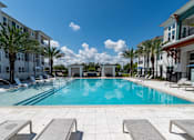 Thumbnail 28 of 60 - A swimming pool surrounded by lounge chairs and palm trees.
