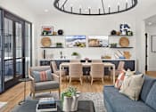 Thumbnail 15 of 20 - A living room with a grey couch, a grey armchair, a wooden dining table with chairs, a grey rug, a grey coffee table, a grey cushion, a grey throw pillow, a grey throw blanket