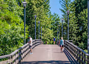 Thumbnail 49 of 50 - A man and a woman are walking on a bridge with street lamps on both sides.